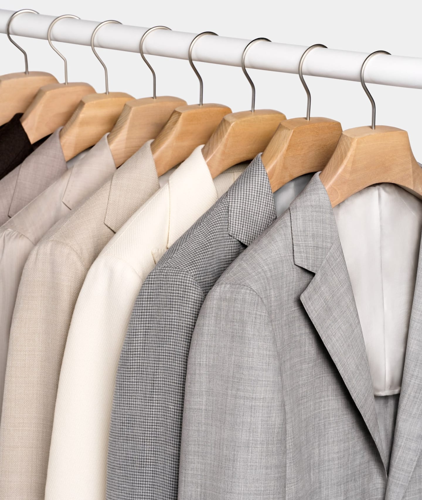Vestes de costume gris clair, à carreaux, et marron clair, sur cintres.